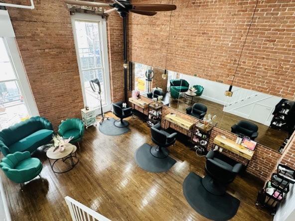 Spacious salon with brick walls, big mirrors, and comfortable seating area for clients.