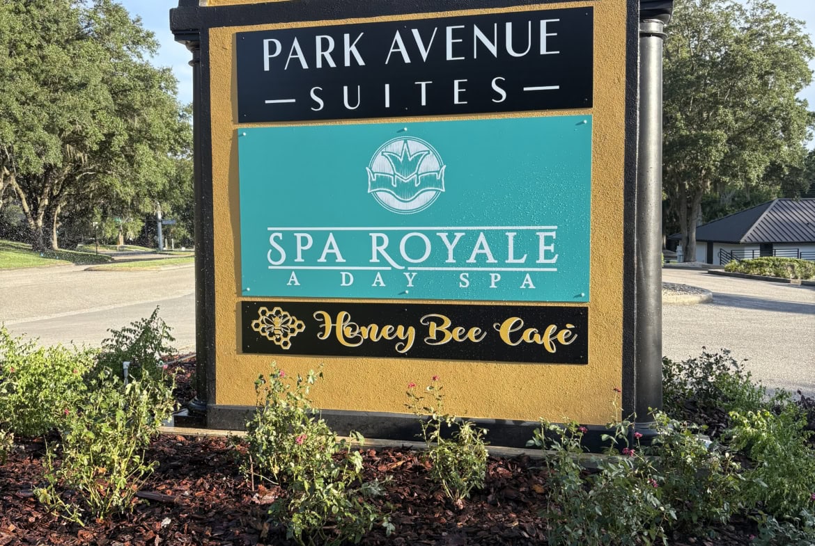 Bright outdoor sign for Salon Renter featuring nearby businesses, highlighting branded signage and landscaping details.