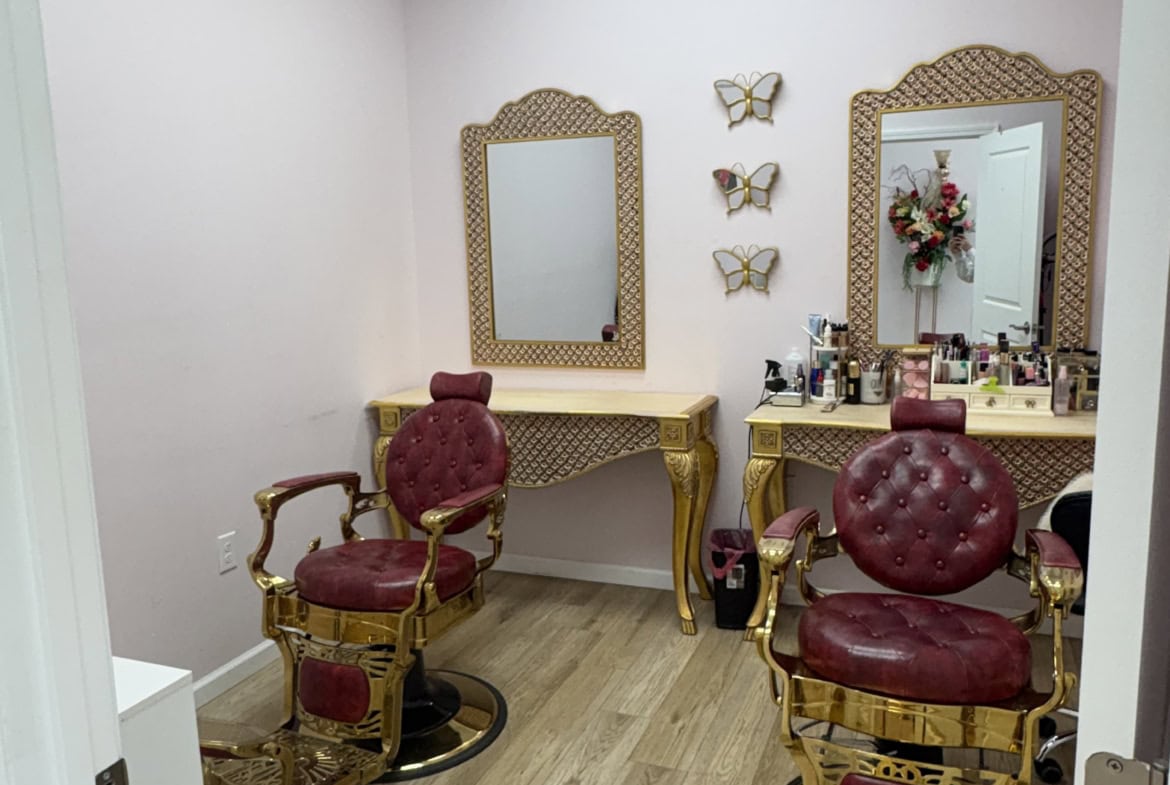 Elegant salon chairs with gold accents and plush red upholstery in a chic, well-lit hair station.