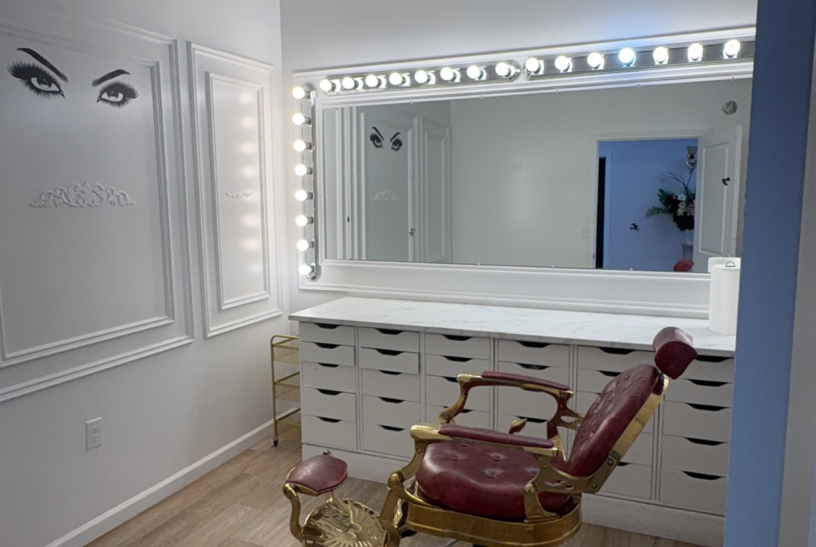 Bright salon vanity with illuminated mirror, vintage styling chair, and organized drawers for beauty professionals.