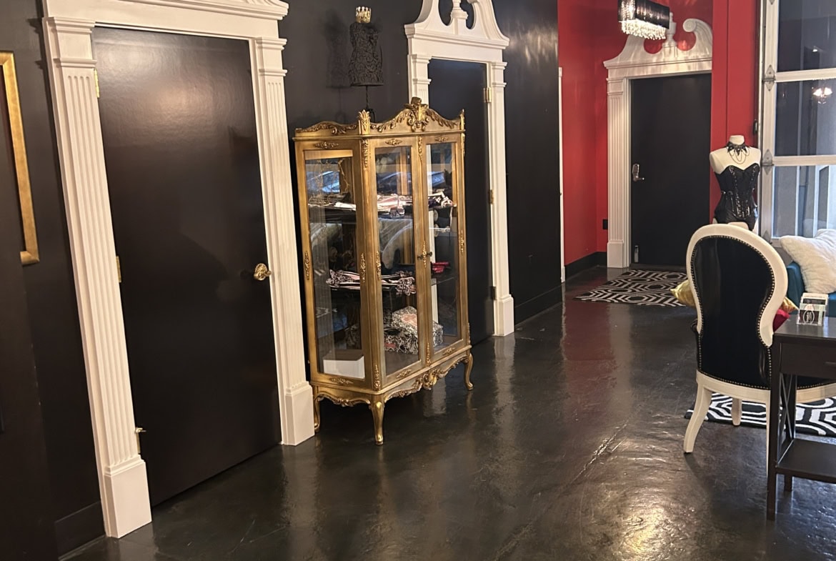 Beautiful salon waiting area featuring vintage doors, decorative display cabinet, and chic furniture.