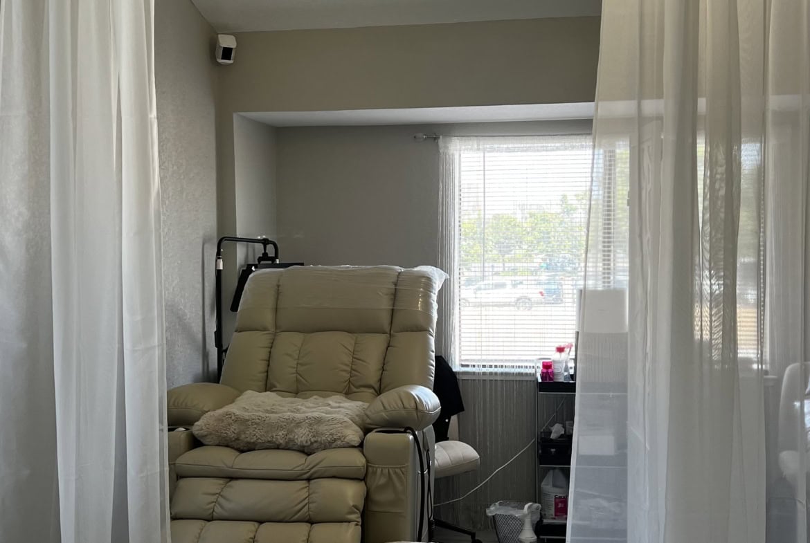 Comfortable beige massage chair in a cozy salon treatment room with soft lighting.