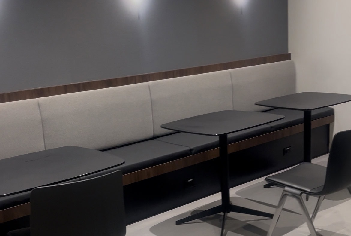 Modern salon waiting area with stylish black tables and chairs, minimalist decor for a premium look.