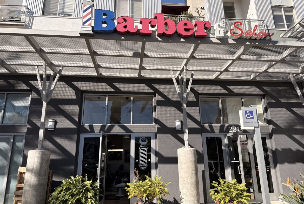 A contemporary barber salon with entrance, plants, and accessible parking space.