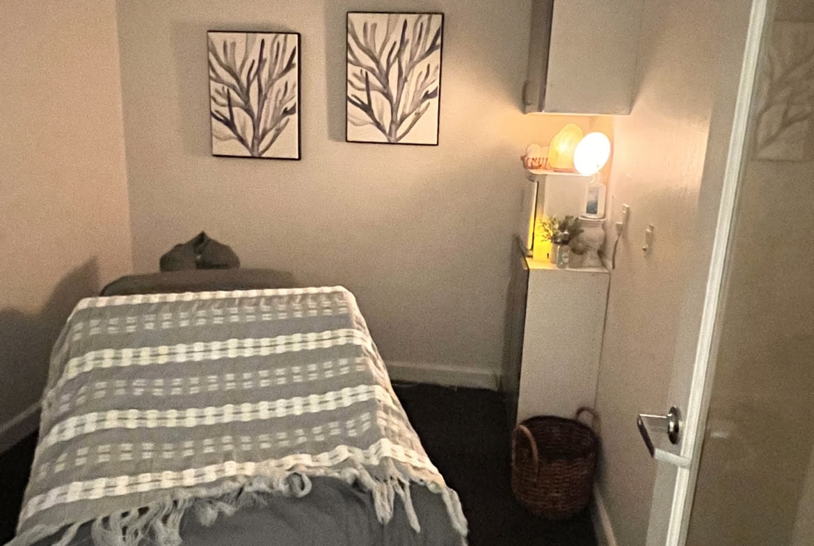 Relaxing massage room with cozy treatment bed and calming decor for spa services.