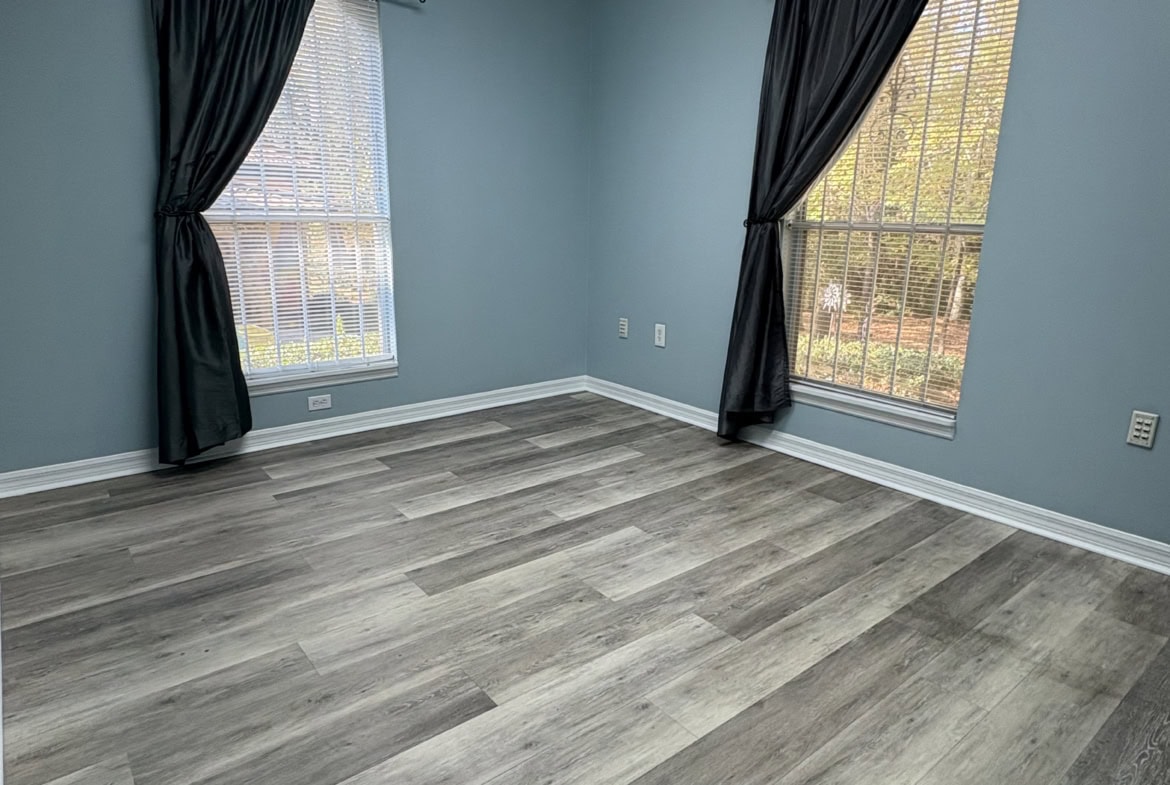 Bright interior space with large windows, blue walls, and laminate flooring, ideal for salon or studio rental.