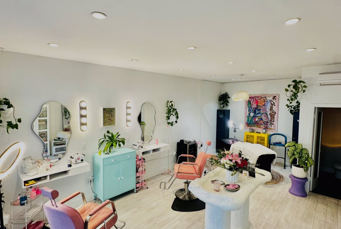Bright, stylish salon interior with makeup stations, chairs, mirrors, and decorative plants.