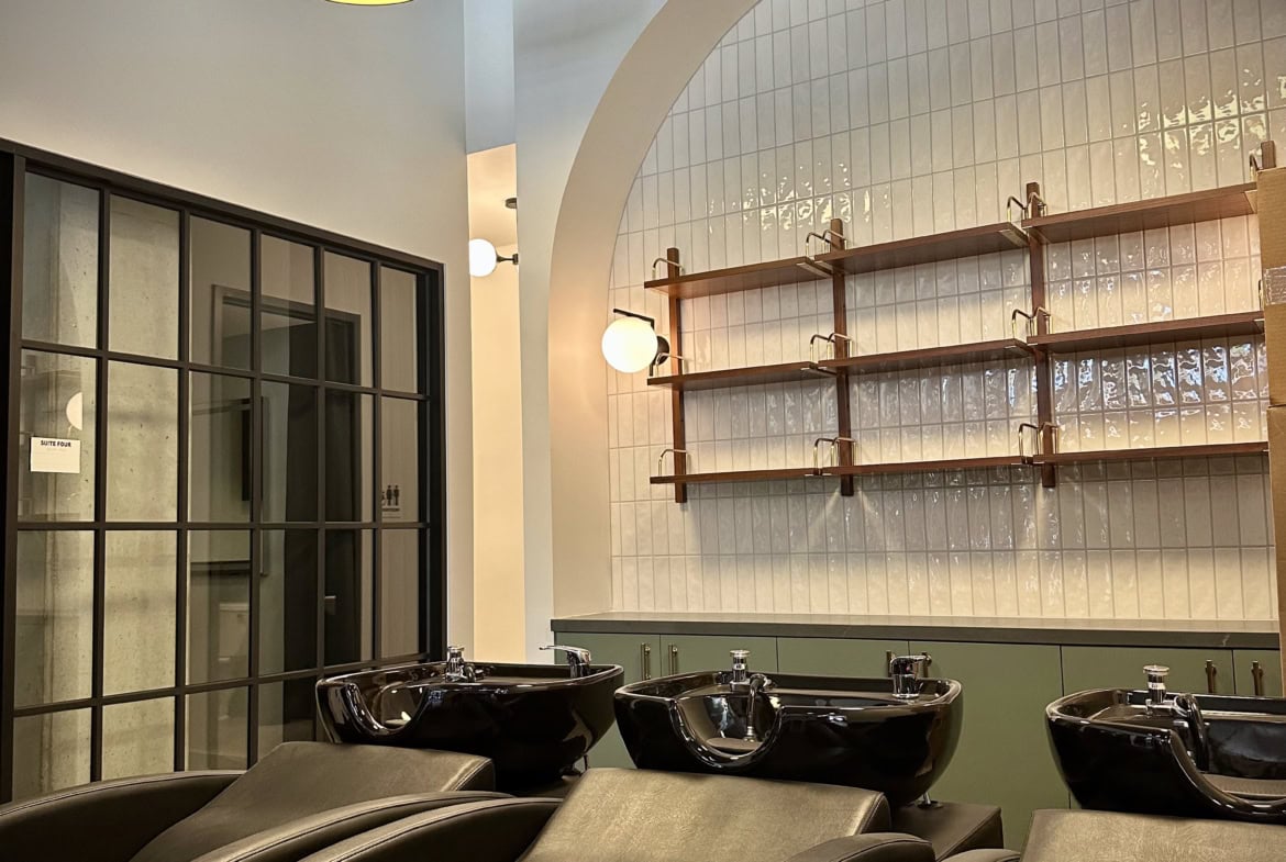 Modern salon hair wash stations with black sinks and comfortable chairs, bright lighting, and stylish decor.