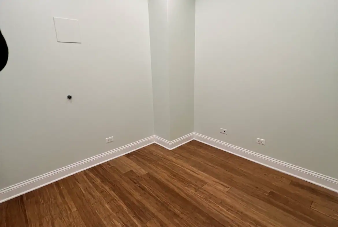 Bright, empty salon rental space with hardwood flooring and white walls, ready for customization.