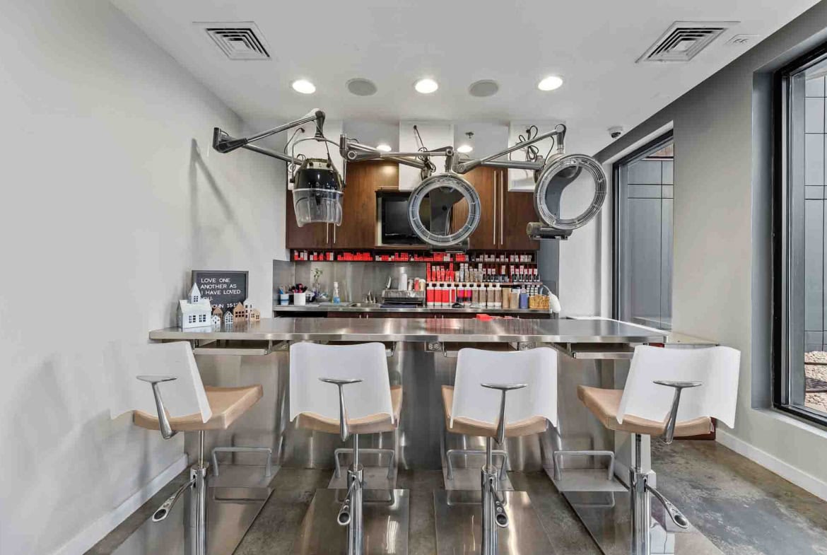 Clean salon station with hair dryers and product display for professional hair styling rental.