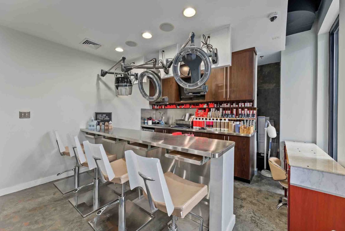 Bright, clean salon space featuring hairdryers, product displays, and seating for styling services.