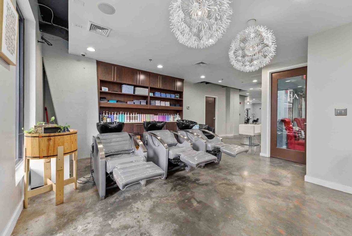 Elegant salon interior with hair washing stations, modern lighting, and professional ambiance.