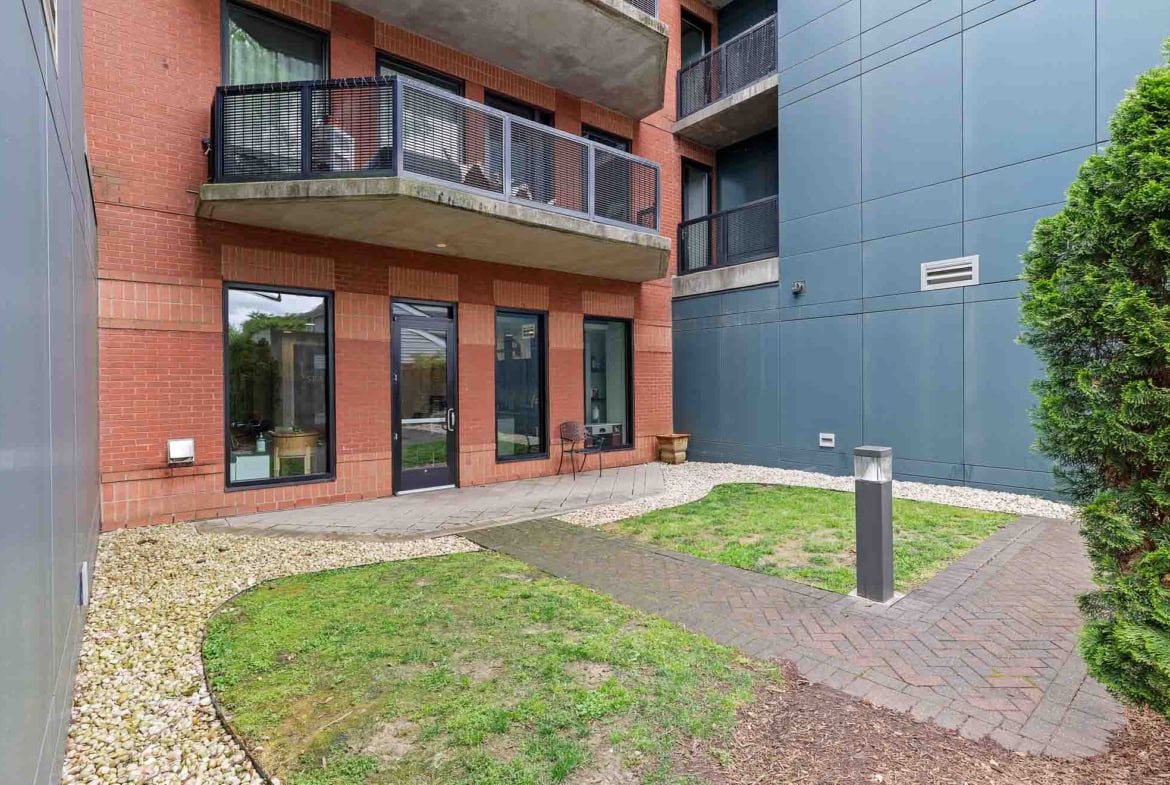 Apartment building exterior with patio and outdoor seating, contemporary brick and blue walls.