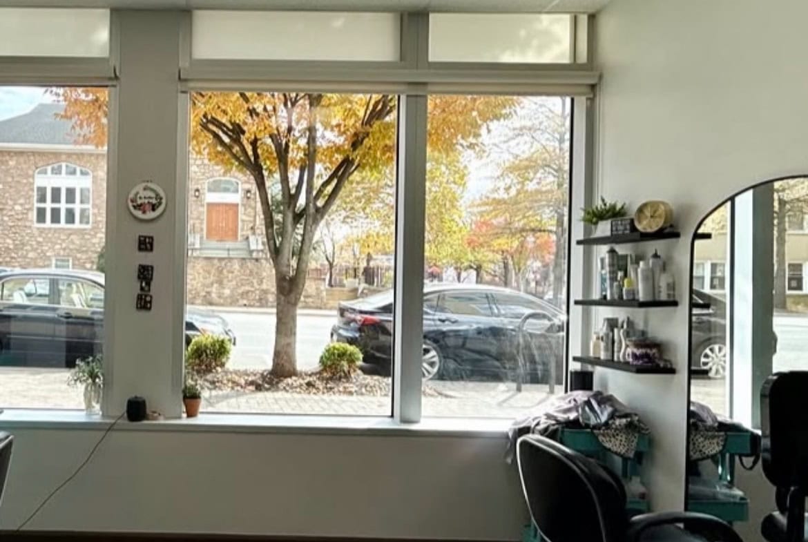 Bright salon interior with large front windows, stylish seating, and hair care products for rent.