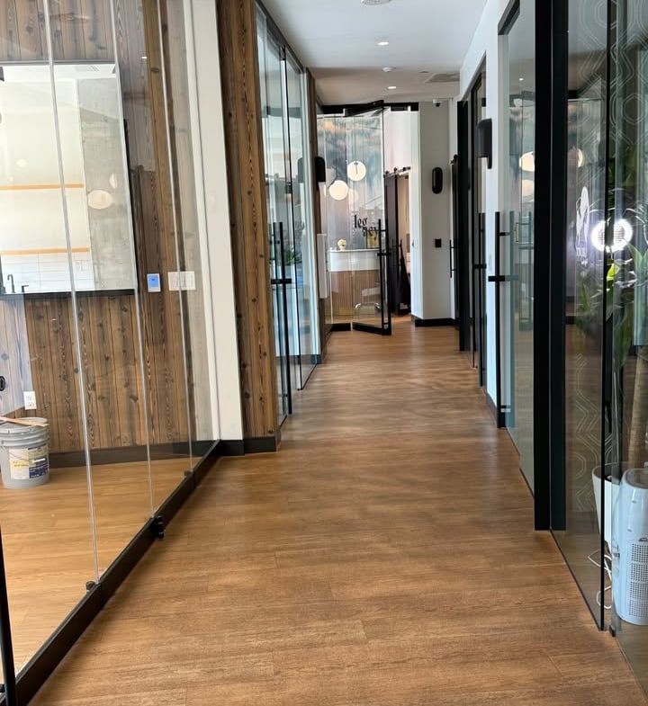 Modern salon hallway with glass doors and wood accents, ideal for salon rental spaces.