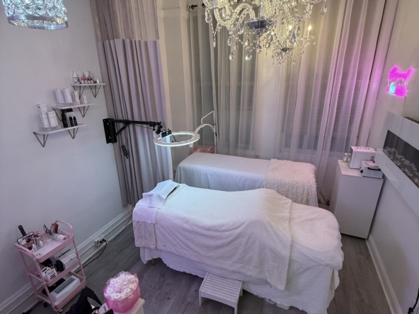 Bright, cozy salon room with massage beds, chandelier lighting, and stylish decor for client relaxation.