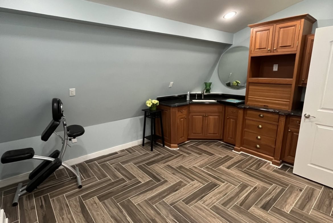 Modern salon rental space with custom cabinetry and herringbone wood-look tile flooring.