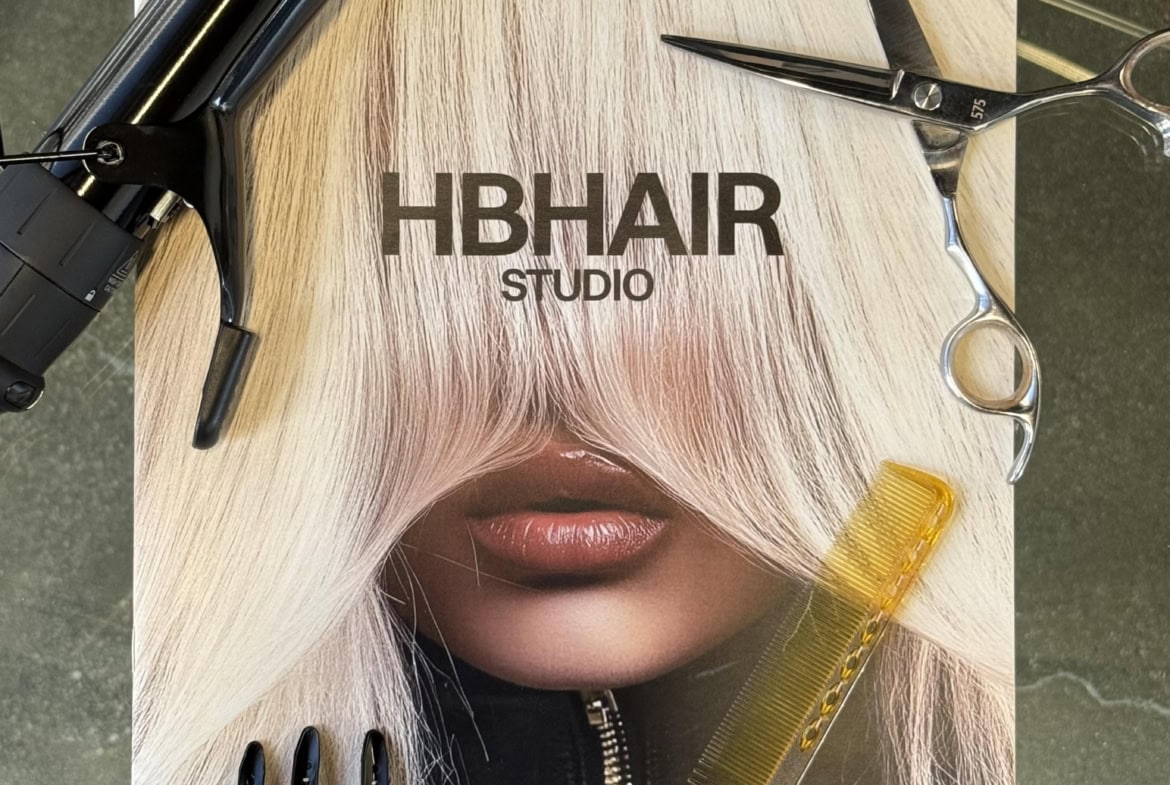 Blow dryer, scissors, hairbrush, and hair color magazine on salon table, professional hair styling tools and accessories.