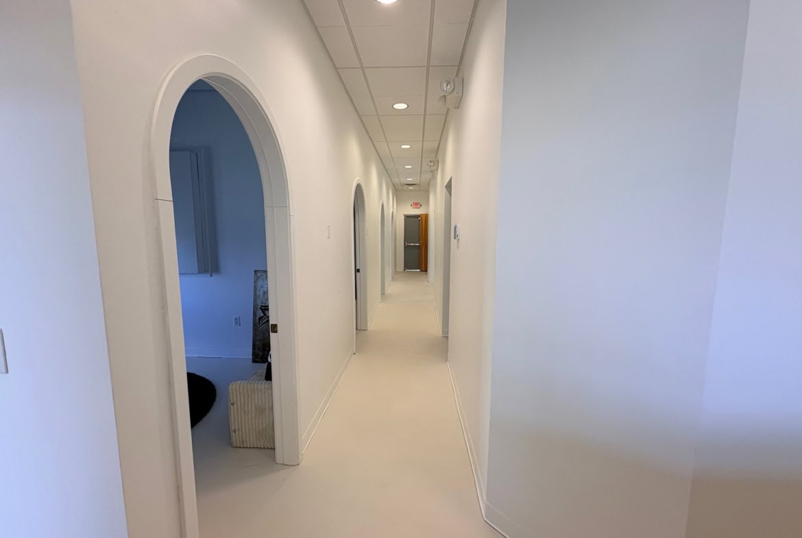 Hallway in a modern salon with white walls and arched doorways, bright and clean interior.