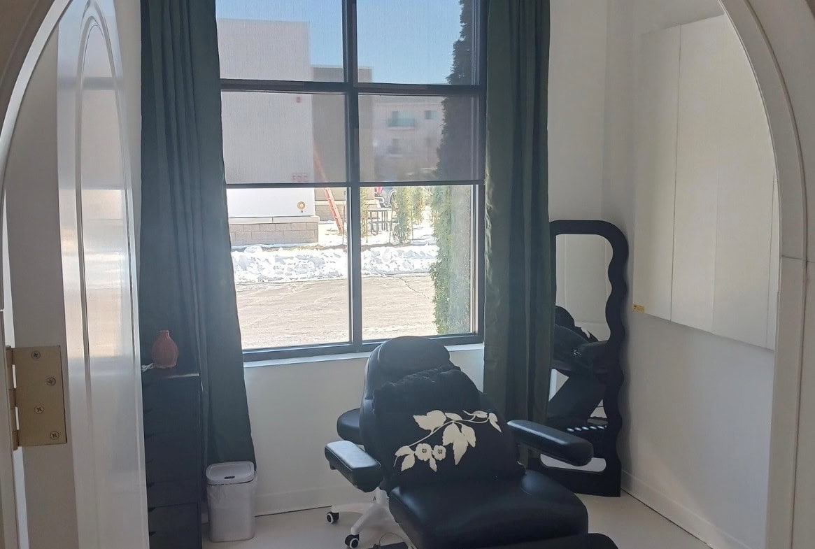 Private beauty treatment room with massage chair and large window.