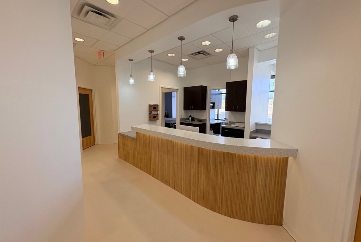 Modern salon reception with wooden counter, pendant lighting, and a clean, welcoming interior design.