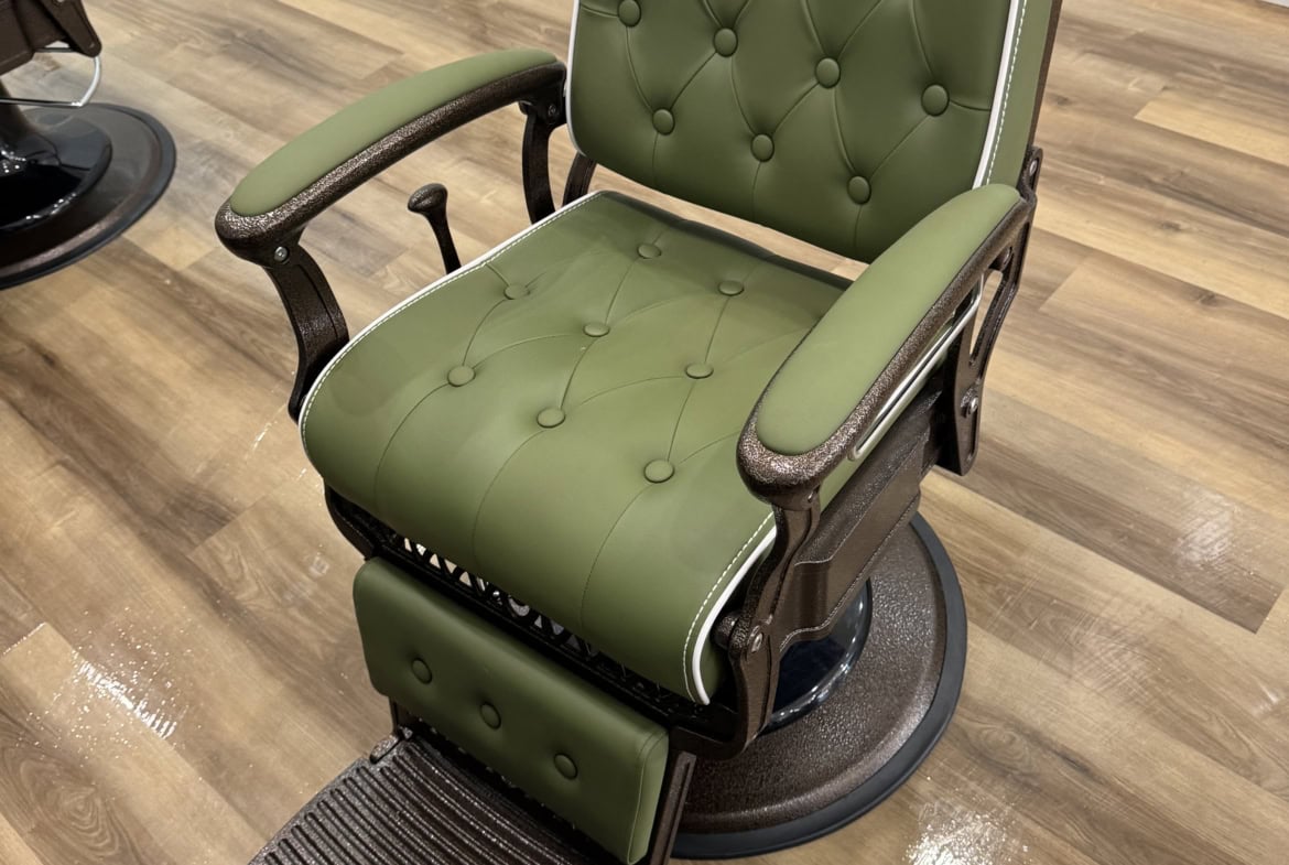 Vintage barber chair with green upholstery and wooden accents.