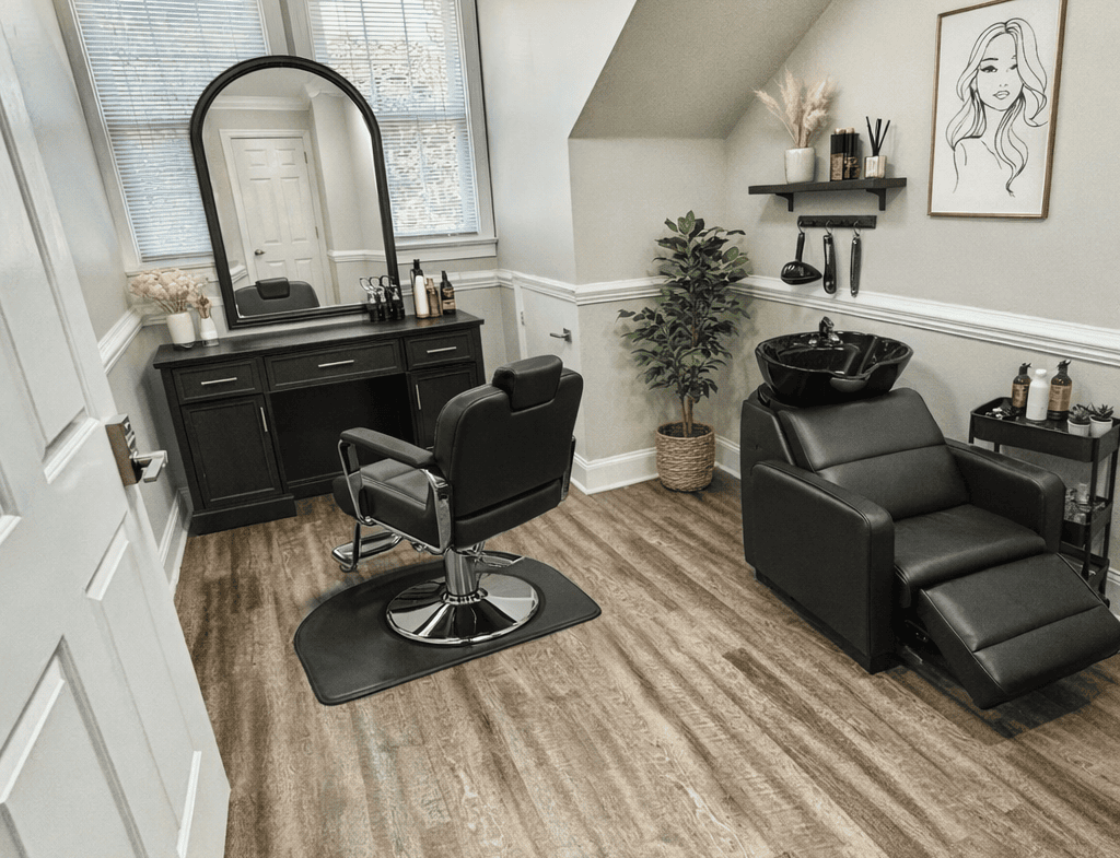 Stylish salon room with black furniture, large window, and cozy decor for hair styling.