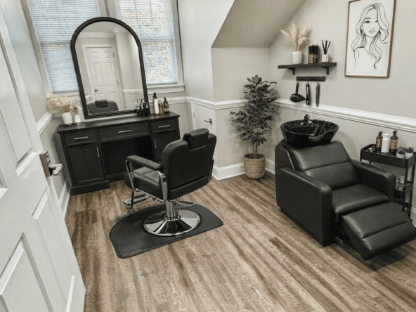 Stylish salon room with black furniture, large window, and cozy decor for hair styling.