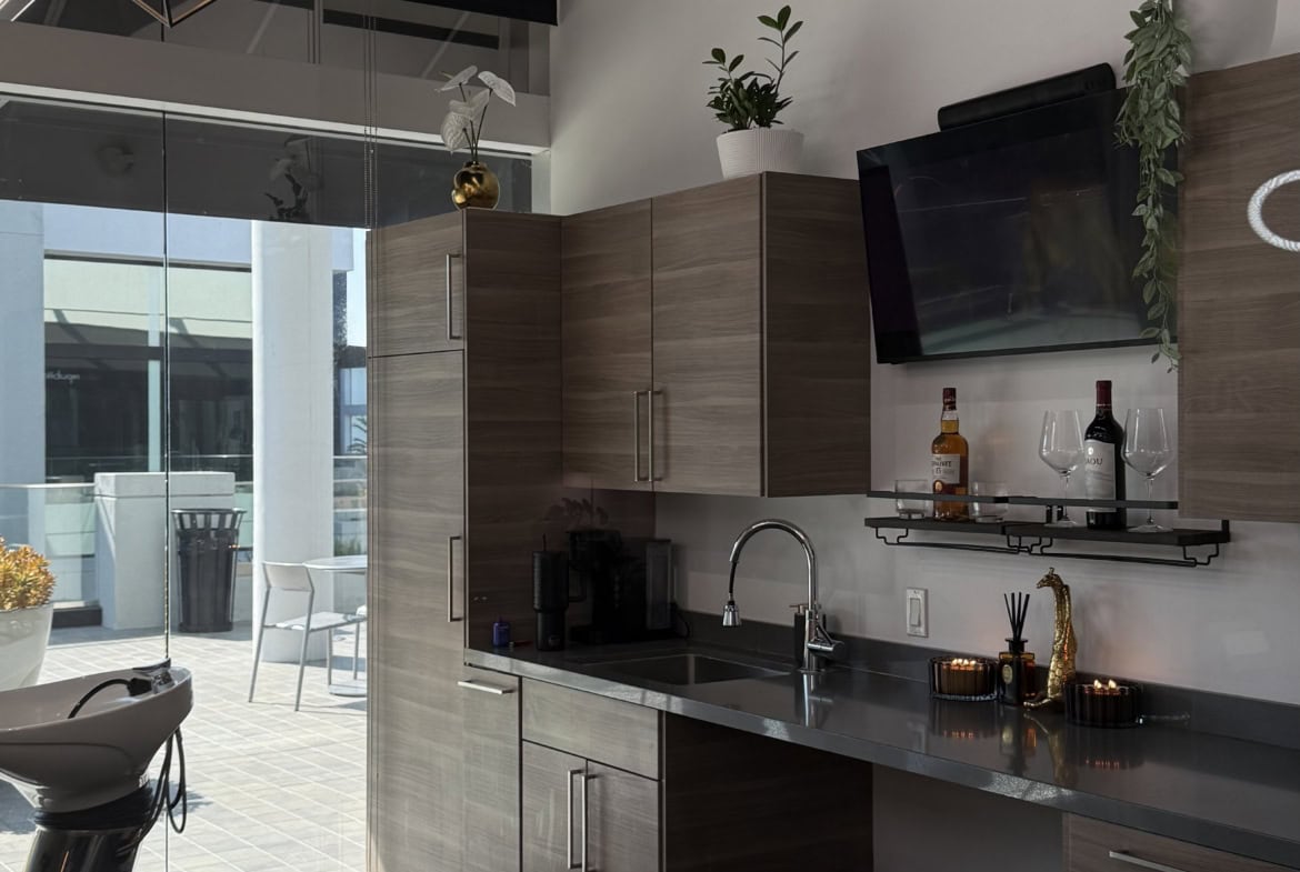 Modern salon kitchen featuring sleek cabinetry, a flat-screen TV, and contemporary lighting. Perfect.