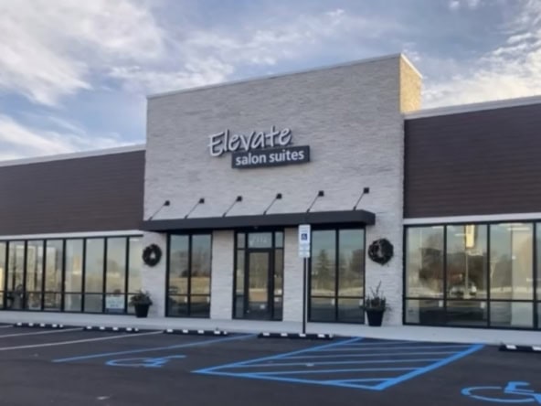 Modern salon suites building with large glass windows and parking lot.