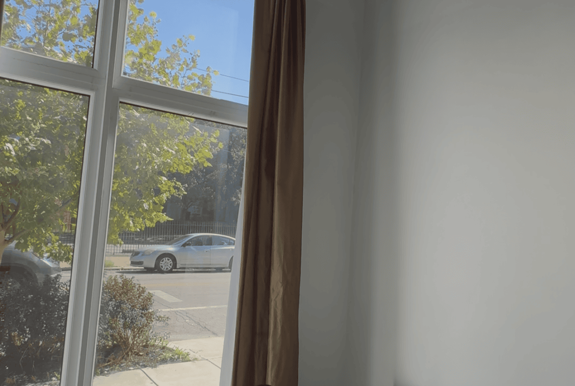 Salon station with large window, black chair, and minimal decor for hair styling.