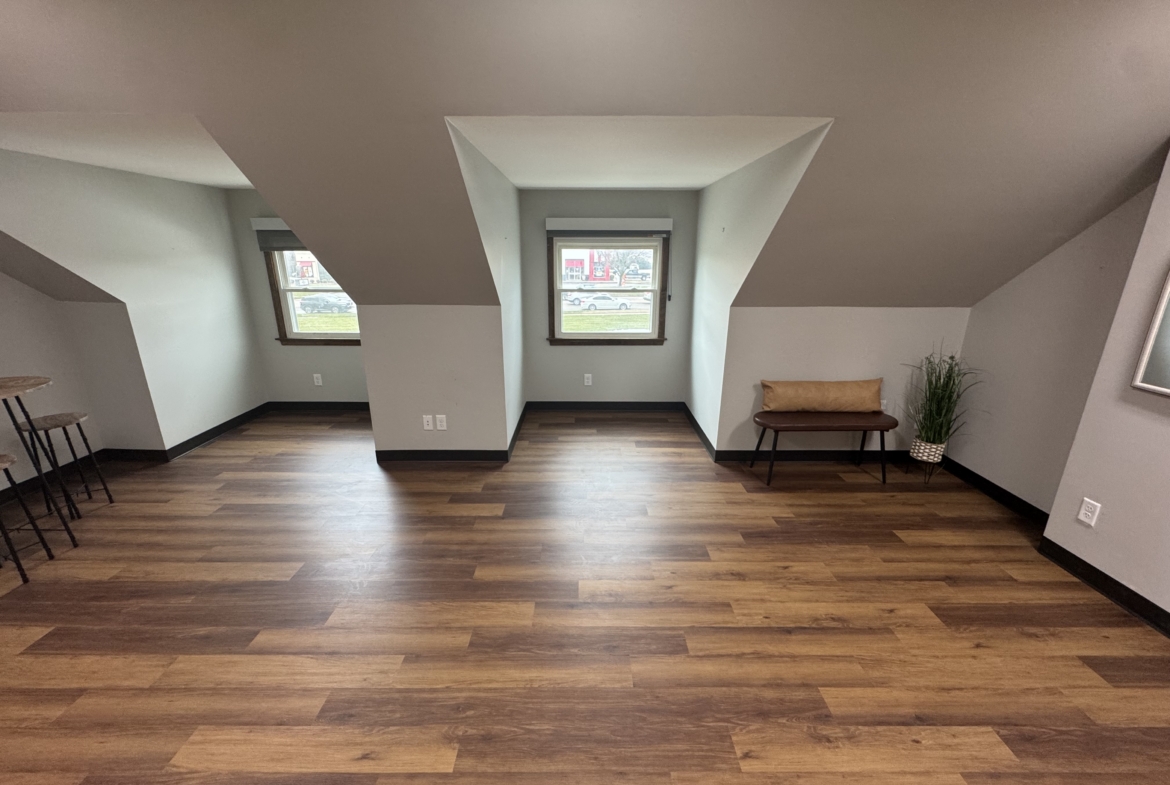 Spacious salon rental with natural light, wooden floors, and cozy seating area.