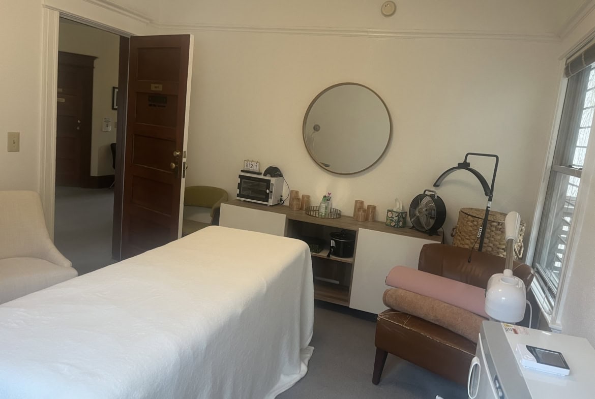 Cozy salon treatment room with massage bed, mirror, and relaxing decor.
