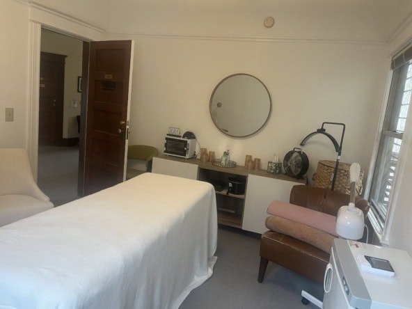Cozy salon treatment room with massage bed, mirror, and relaxing decor.