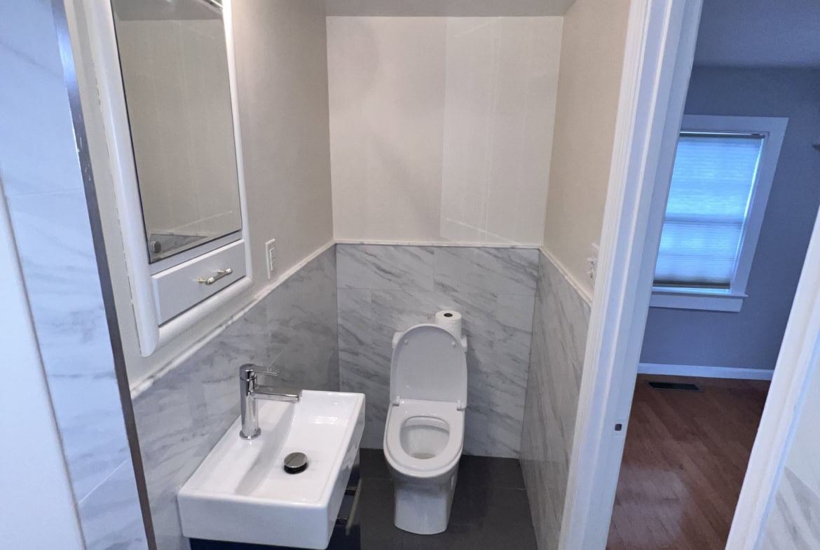 Small salon bathroom with sink and toilet, modern design, bright lighting.