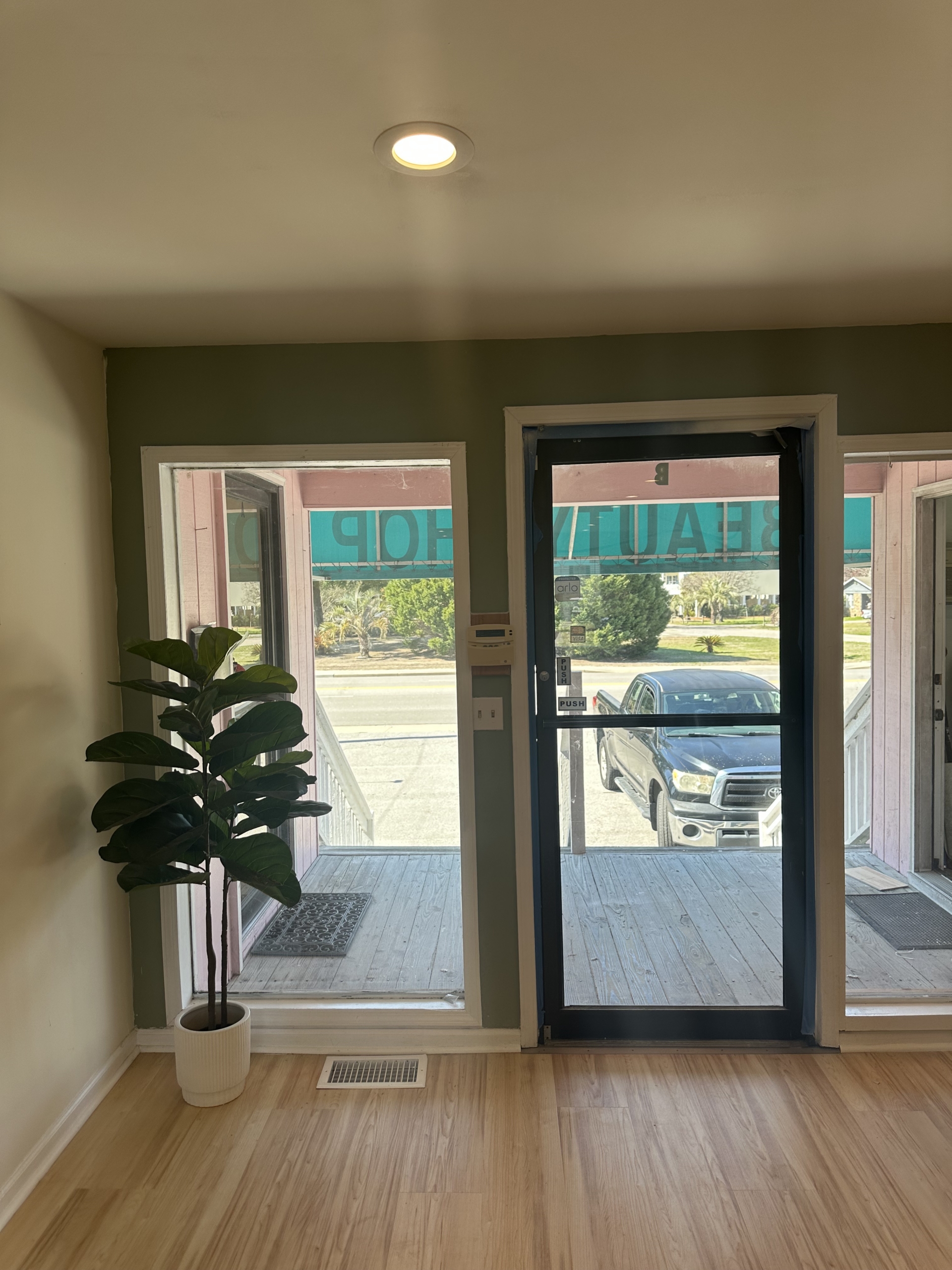 Interior view of salon entrance with large windows and potted plant, showcasing a welcoming space fo.