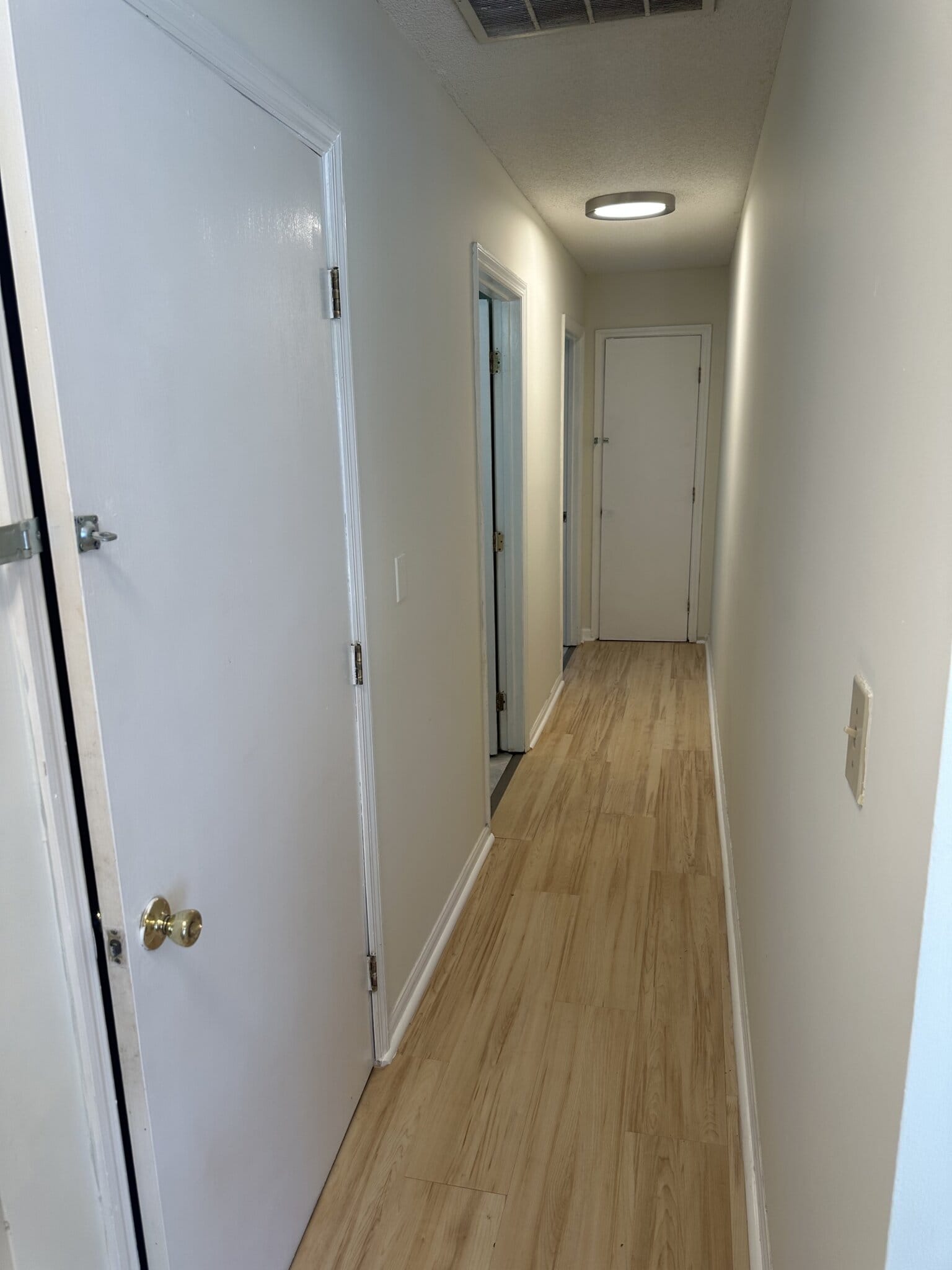 Hallway in a salon rental space with white walls and wooden flooring.