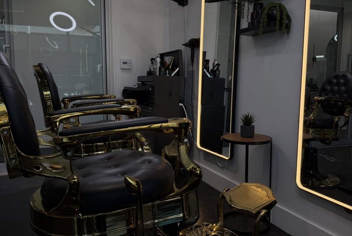 Stylish salon station with black and gold chairs, illuminated mirrors, and professional hairdressing.