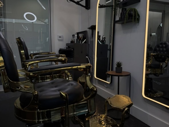 Stylish salon station with black and gold chairs, illuminated mirrors, and professional hairdressing.
