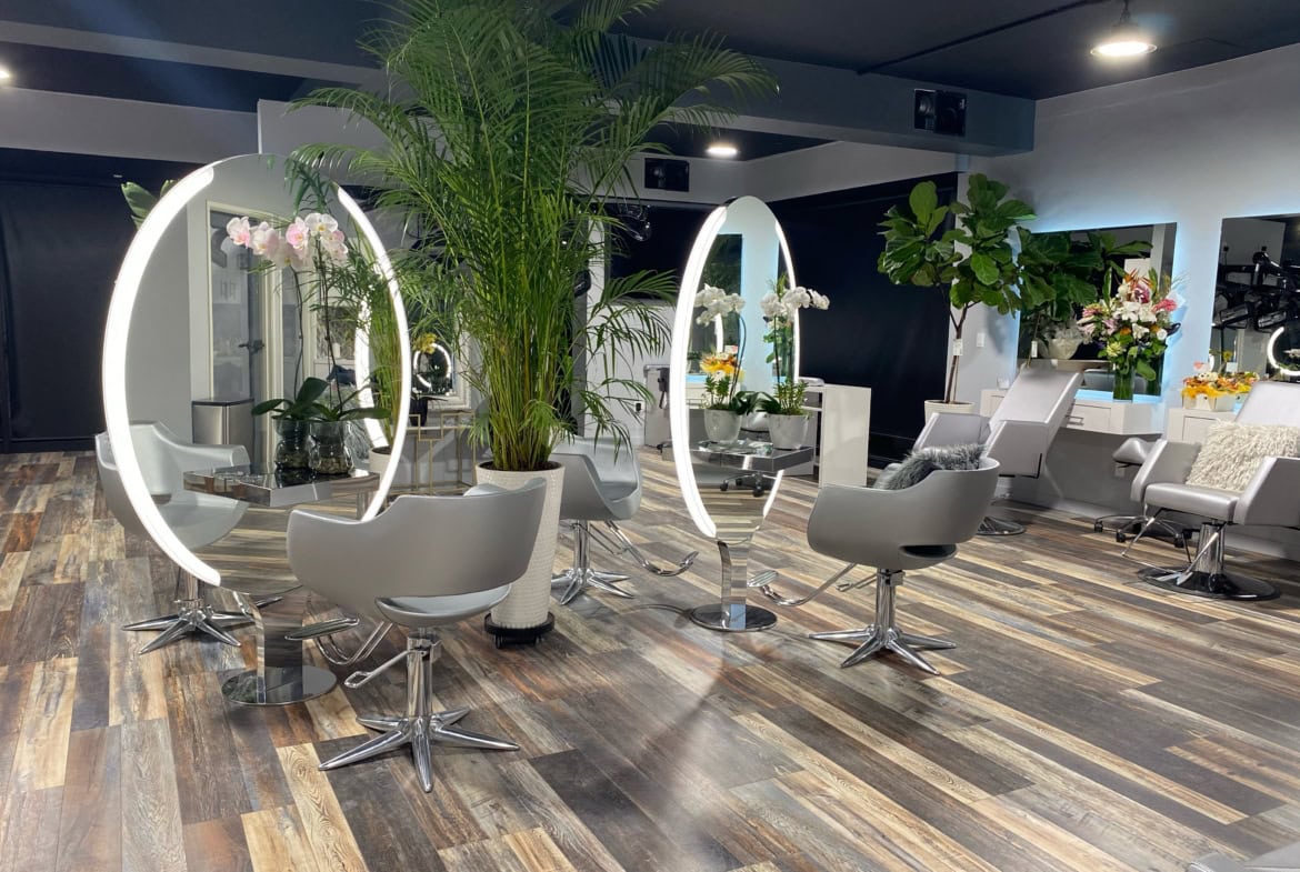 Modern hair salon with illuminated mirrors, styling chairs, and fresh floral decor for a professiona.