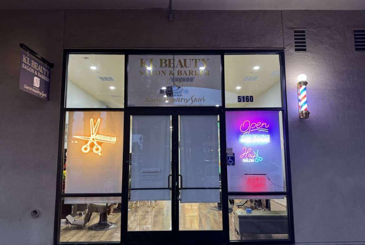 Modern salon storefront with neon signs and glass doors, inviting clients inside.