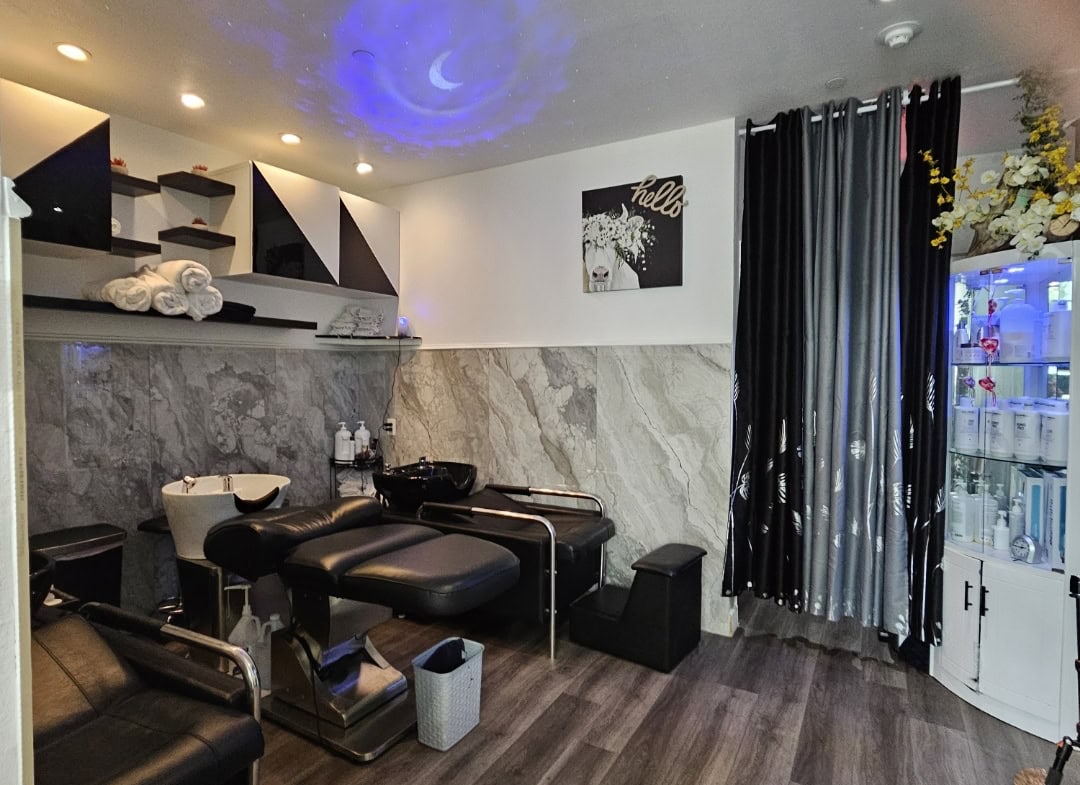 Cozy salon treatment room with black furniture, marble walls, and ambient lighting.
