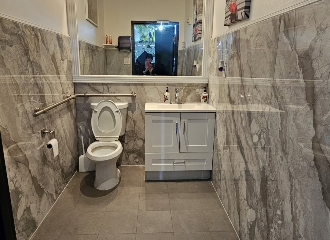 Modern salon bathroom with marble walls and a white sink.