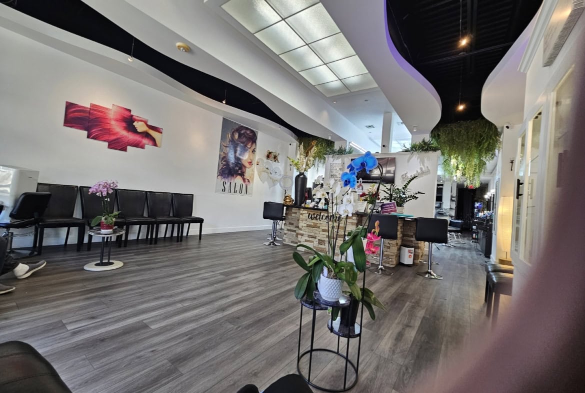Modern salon interior with plants, seating, and stylish decor for a welcoming atmosphere.