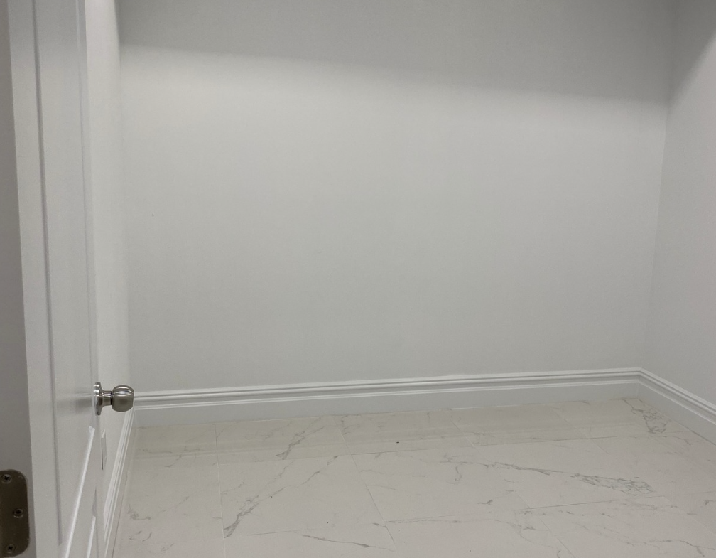 Empty salon space with white walls and marble flooring, ideal for beauty professionals seeking renta.