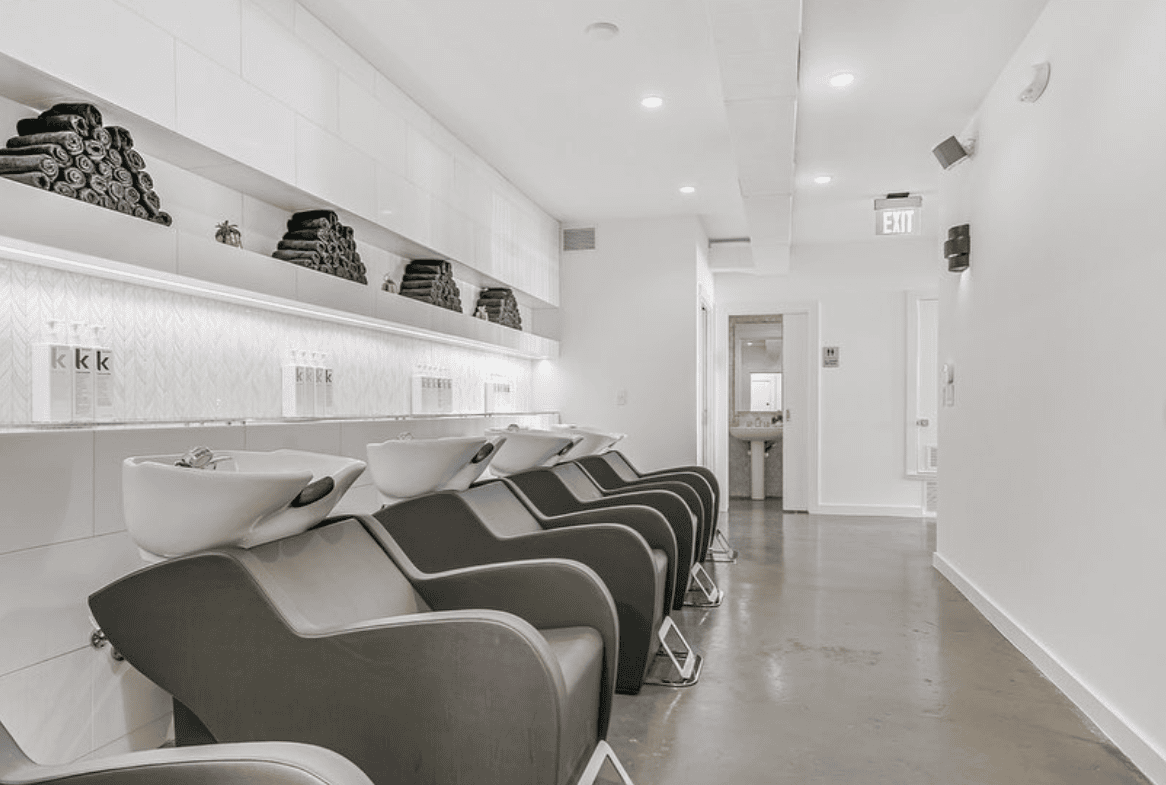 Elegant salon interior with hair wash stations, shelves with towels, and bright lighting for a profe.
