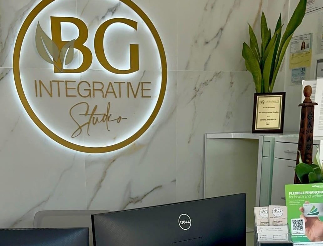 BG Integrative Studio sign on marble wall with plants and reception desk.