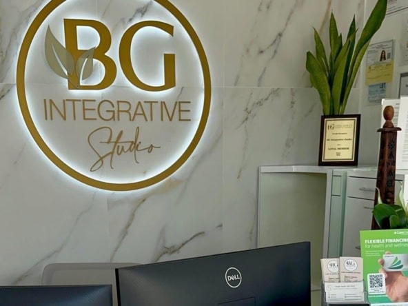BG Integrative Studio sign on marble wall with plants and reception desk.