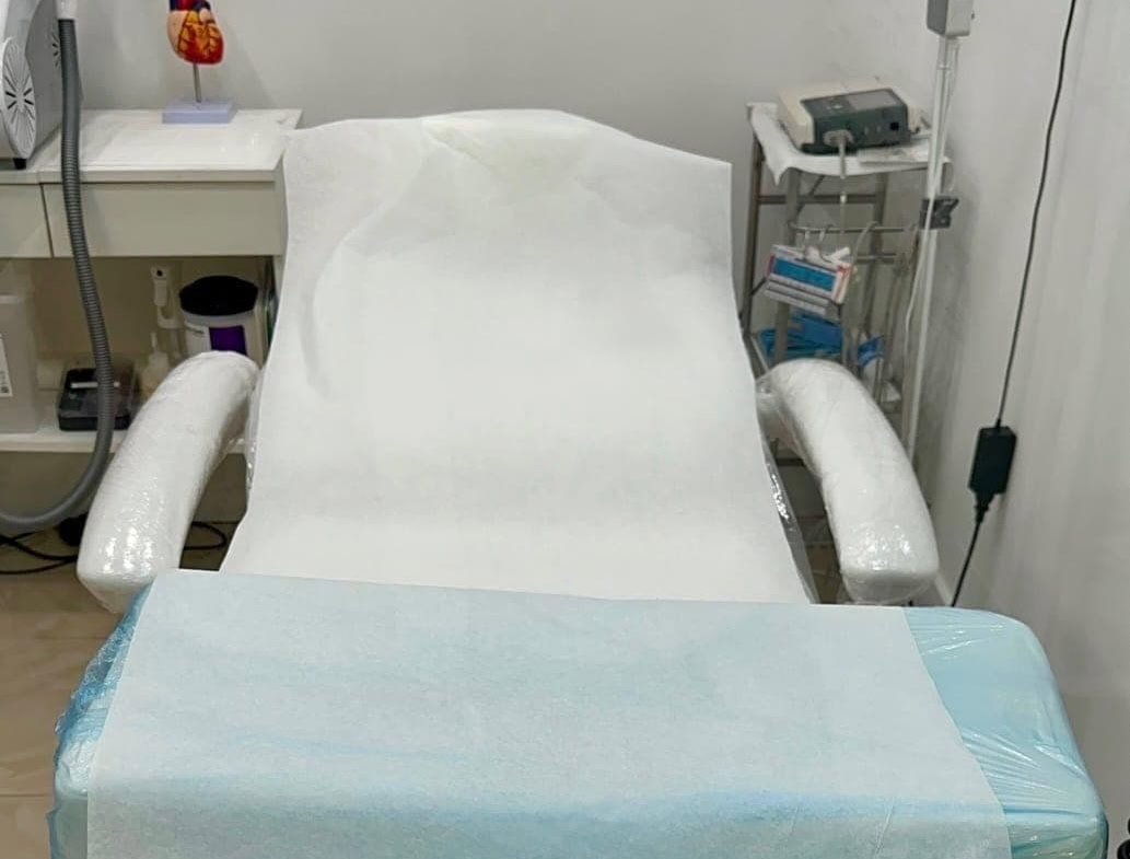 Hair salon treatment chair with armrests and disposable cover.