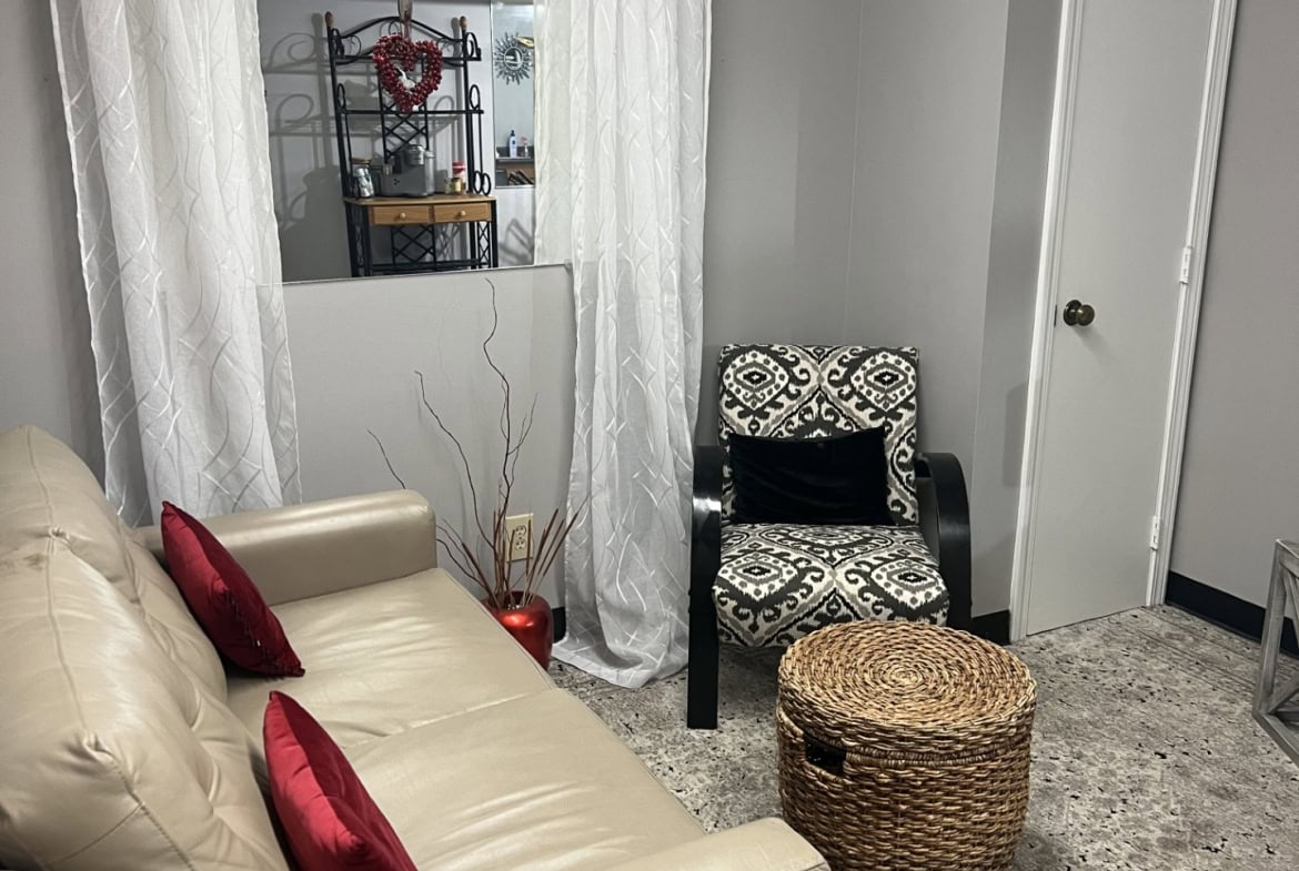 Comfortable salon waiting area with beige sofa, decorative pillows, and stylish armchair.